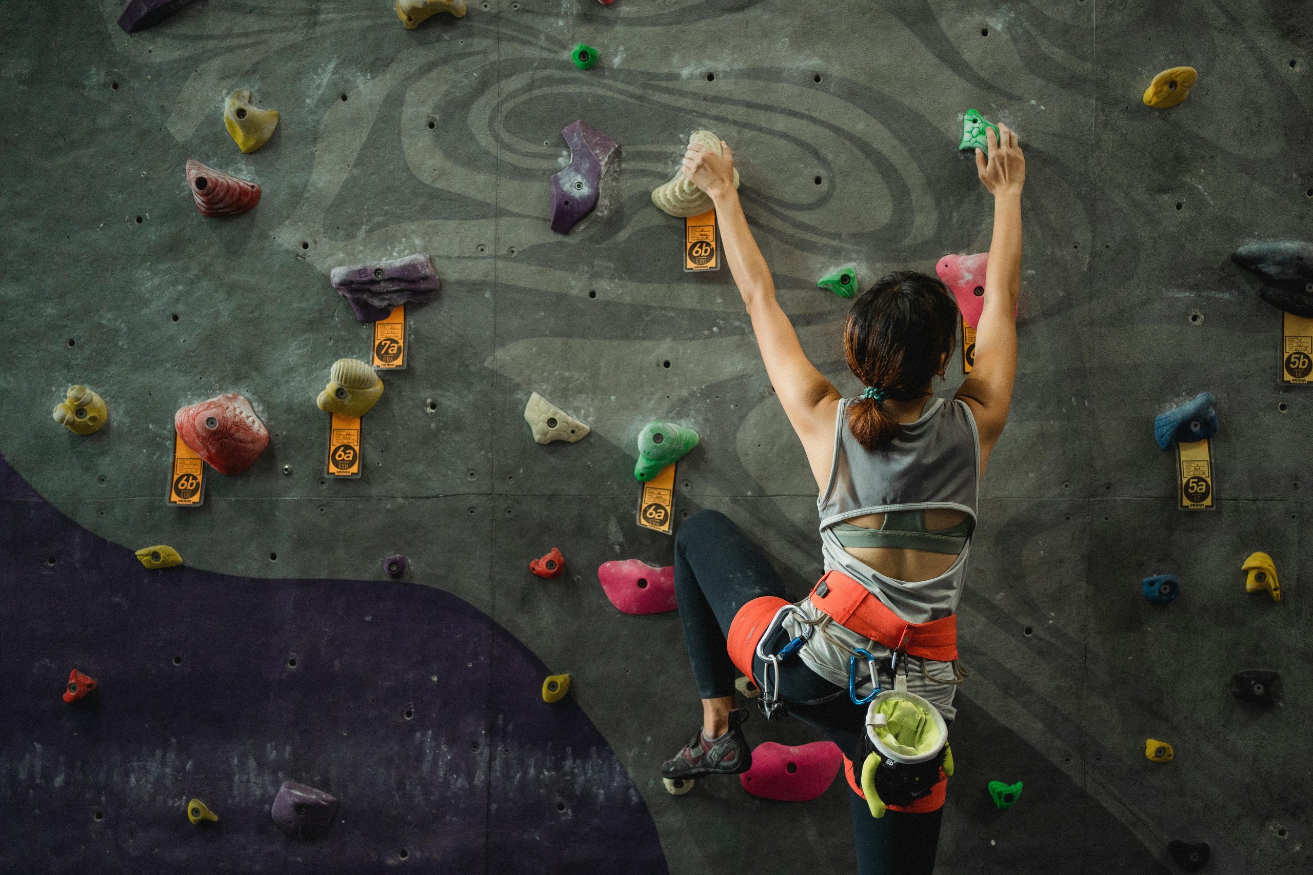 A young woman rock climbing indoors, showcasing strength and determination.